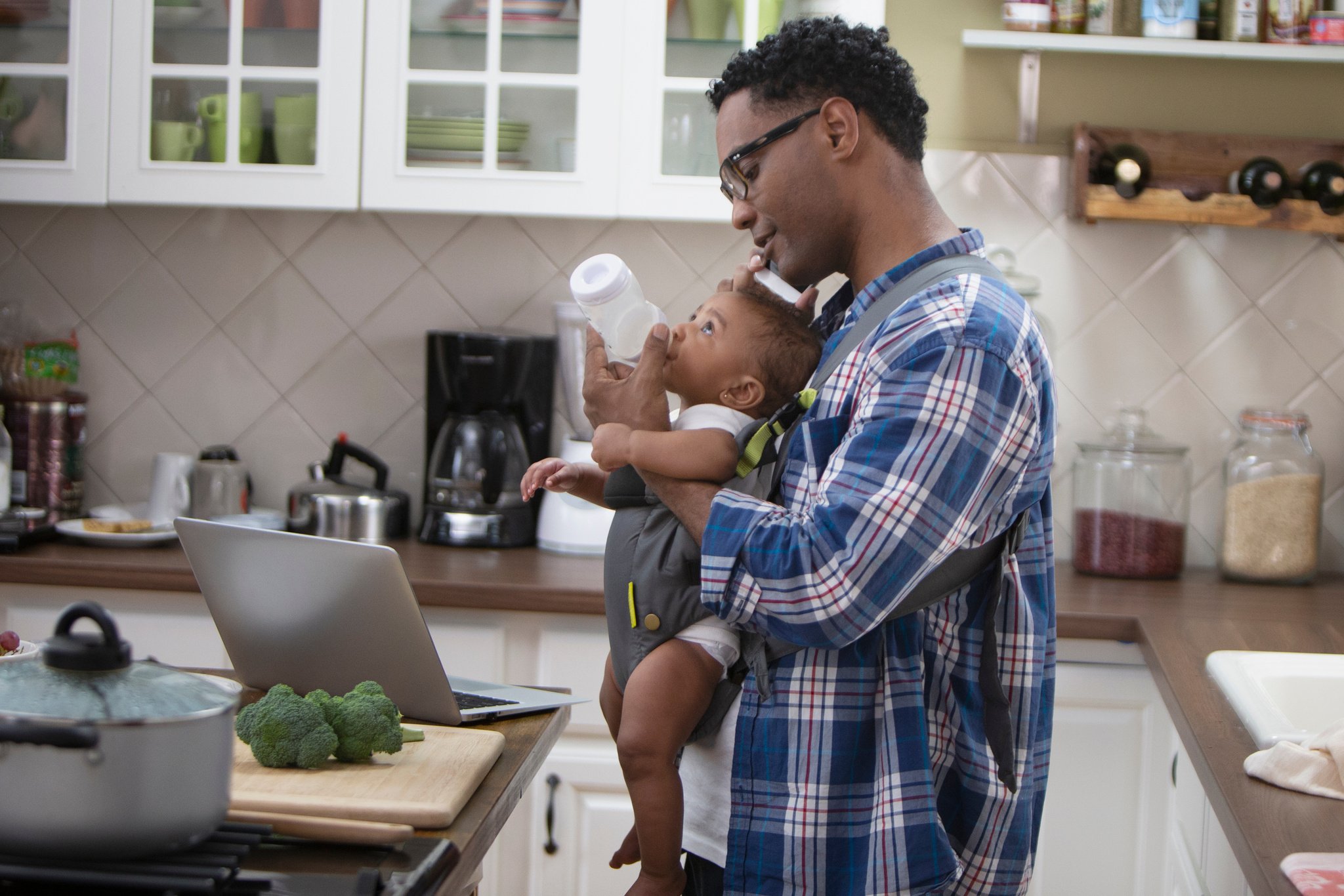 Single parent working from home holding baby